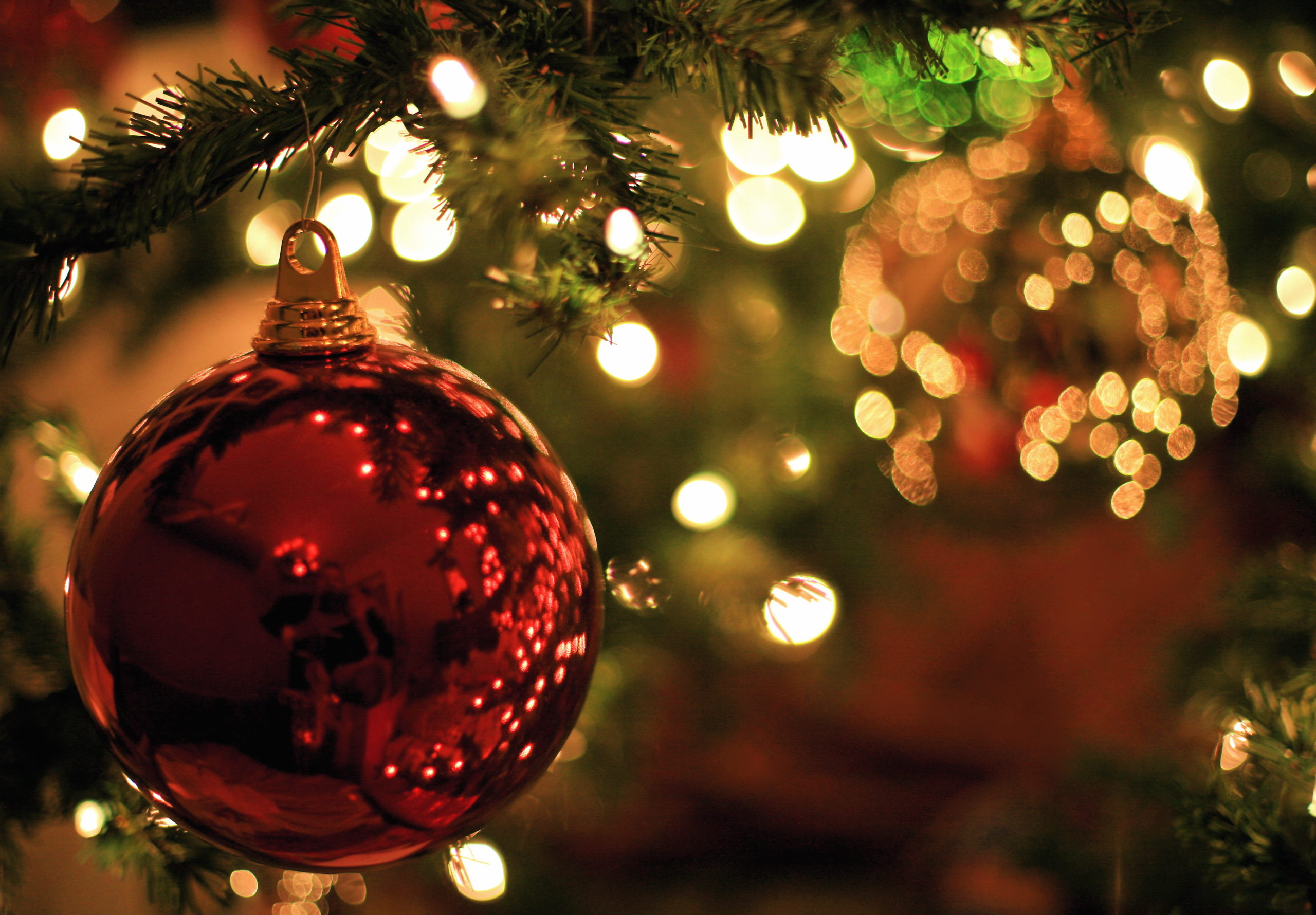Colour photo of a red Christmas Carols bauble and lights.