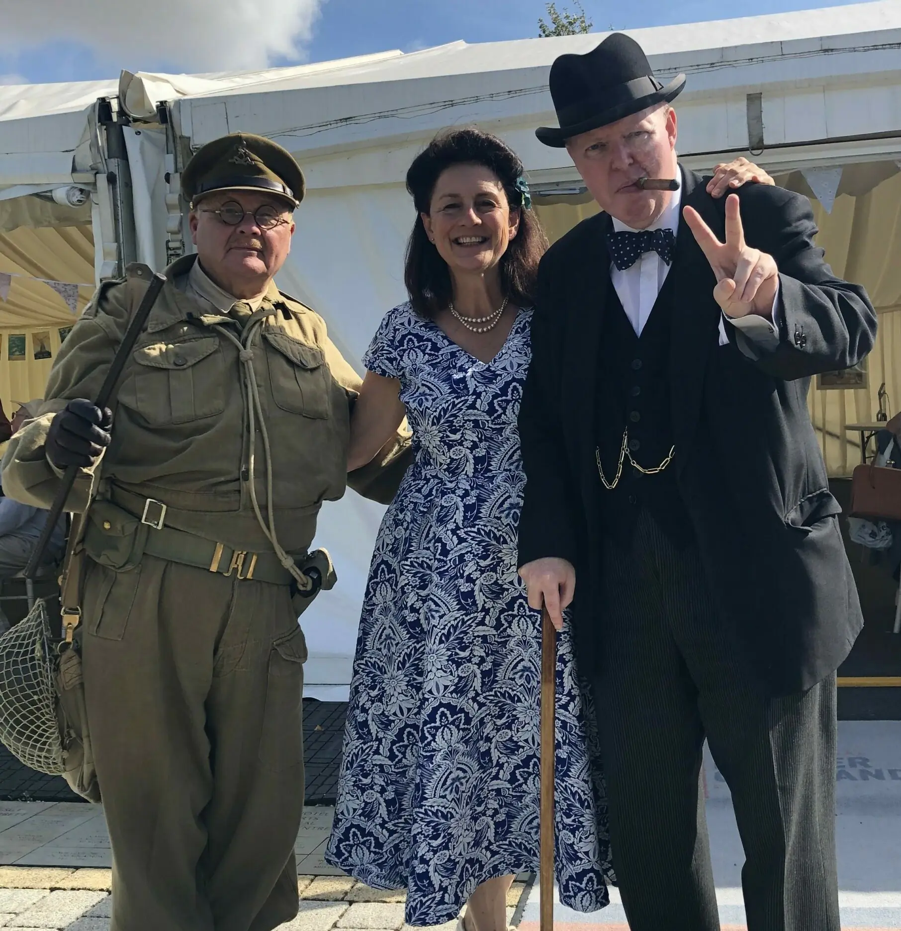 Colour photo of 3 people in 1940's costumes including Churchill and Capt Mainwaring