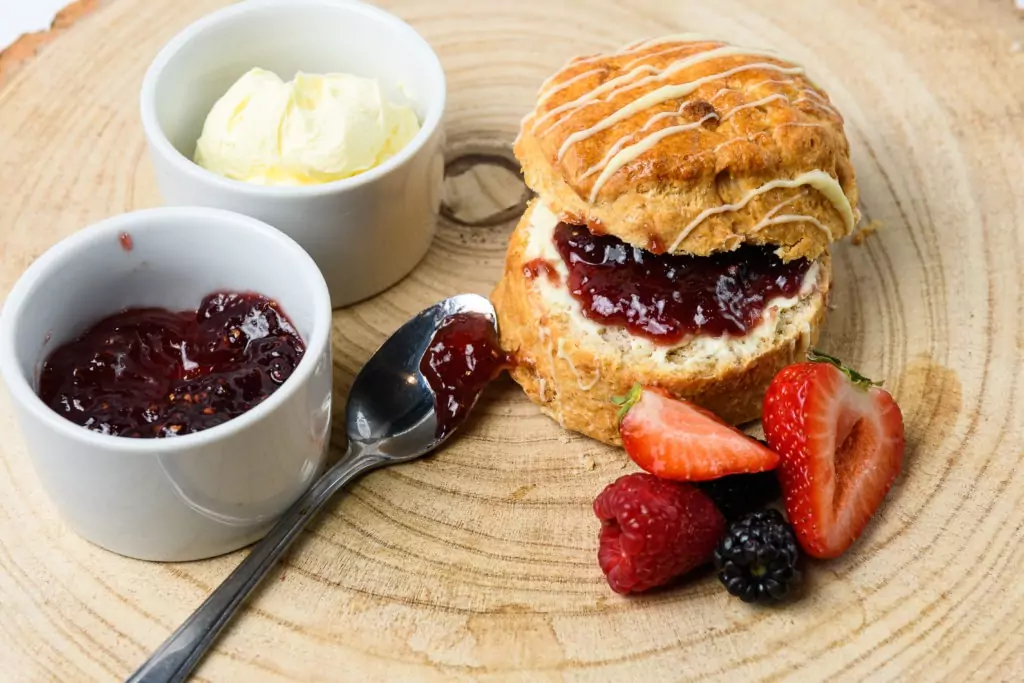 A colour photo of a scone with jam, clotted cream and fruit