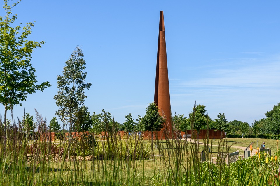 The memorial Spire at the IBCC from the gardens. Blue sky in the background.