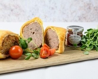 A colour photo of a sausage roll with onion relish and rocket salad