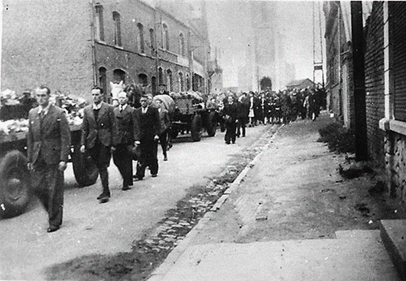 Black and white wartime image of a funeral cortege and onlookers lining the street