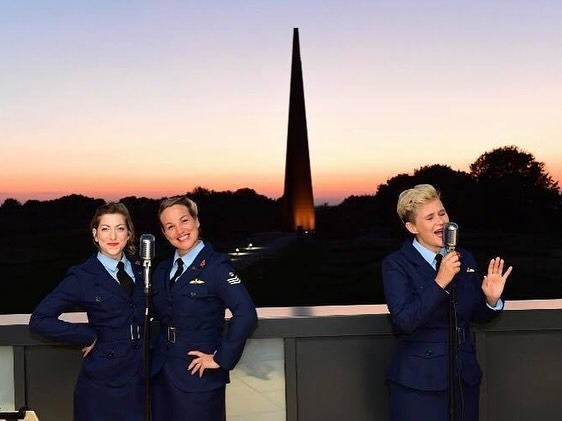 Colour photo of 3 ladies in RAF uniform and the Memorial - Blighty Belles