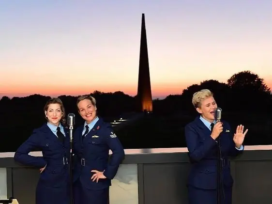 Colour photo of 3 ladies in RAF uniform and the Memorial - Blighty Belles