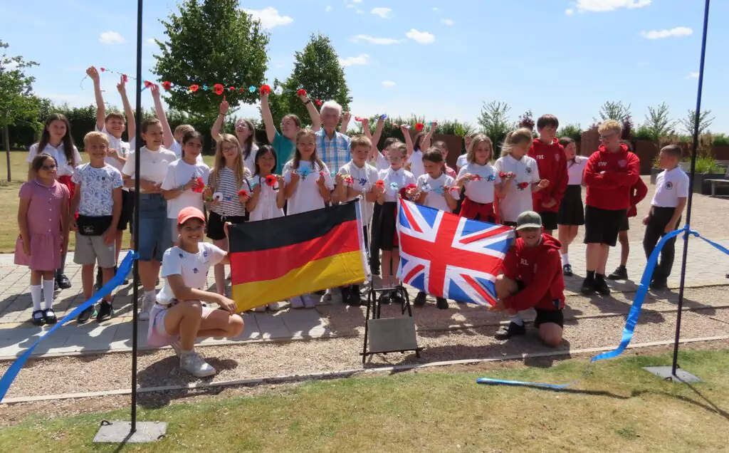 Colour photo of children from Germany and UK with a stone for friendship and flags and peace bunting